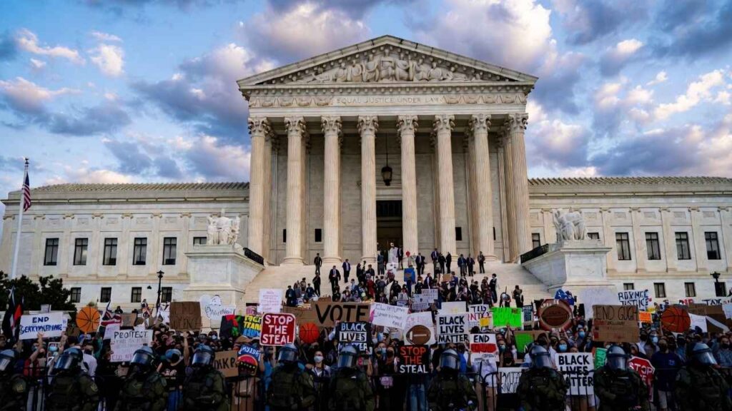 Supreme-Court-Trans-Athletes-US-Supreme-Court-building-with-protesters-holding-signs-about-transgender-athletes-and-womens-sports-rights-during-landmark-2026-case-hearing