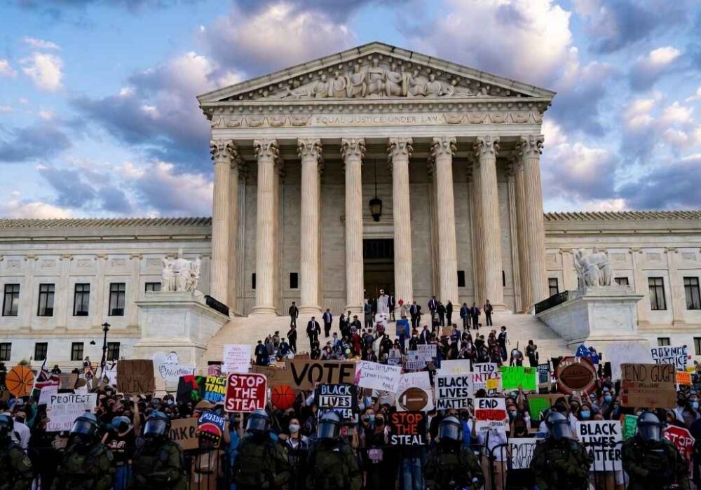 Supreme-Court-Trans-Athletes-US-Supreme-Court-building-with-protesters-holding-signs-about-transgender-athletes-and-womens-sports-rights-during-landmark-2026-case-hearing
